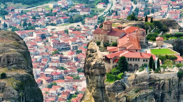 Aerial drone shot of the Holy Monastery of St. Stephen in Meteora, Greece. Panning view of the accessible nunnery complex and the town of Kalabaka in the valley below