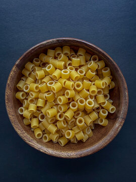 Dry Ditalini Pasta in Wooden Bowl on Dark Background