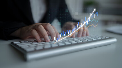 Fototapeta premium Business professional working on a keyboard while analyzing market trends through digital graphs, showcasing the intersection of technology and finance in modern workplaces. Impute