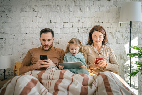 Family members using digital devices in bed