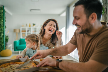 Obraz premium Family enjoying pizza dinner together at home