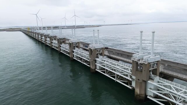 several cyclists cross roadway atop oosterscheldekering activity dual purpose nature iconic coastal infrastructure netherlands delta works tourism transportation maritime engineering 