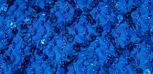 Shimmering blue sequins on textile fabric in sunlight  background
