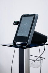 RF lifting device with touchscreen display showing settings is positioned on a sleek stand in a beauty clinic, ready for cosmetic dermatology treatments with copy space