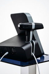 Cosmetic dermatology device with a sleek black and silver design, featuring a handheld applicator and a control panel, positioned on a modern stand with a clean background