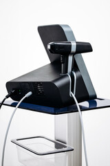 Cosmetic dermatology equipment for RF lifting treatment displayed on a sleek stand with a modern design and connected cables in a clinical setting with copy space
