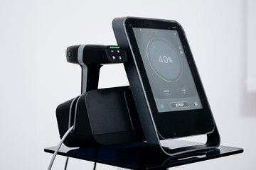 Cosmetic dermatology device with touchscreen display showing 40% progress, placed on a sleek black stand in a modern beauty clinic environment with minimalistic design