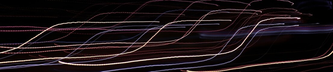 Linear composition. Аbstract long-exposure photograph depicting colorful neon light trails against a dark background.