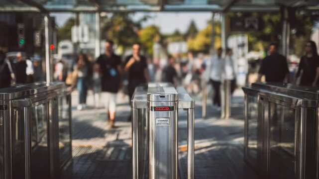 Medium shot focused on land crossing biometric gates where vehicles and pedestrians undergo fingerprint and ID verification processes under surveillance cameras.