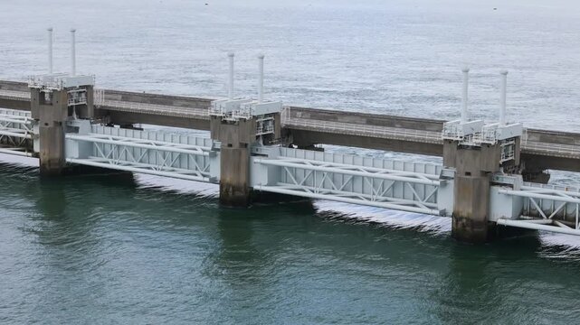 massive concrete piers intricate white metal support trusses anchor barrier against shifting tidal currents eastern scheldt storm surge aerial shot netherlands 