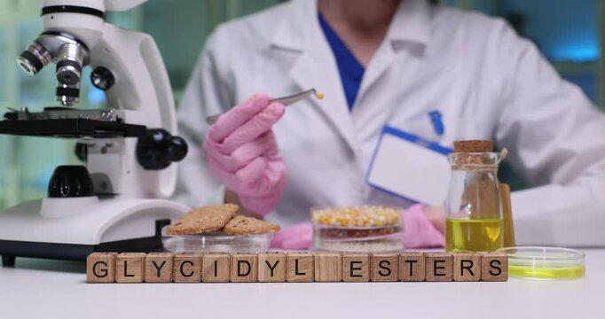 Text Glycidyl Esters on wood cubes and female scientist researches corn seeds in lab. Contaminants formed from natural food constituents analysis