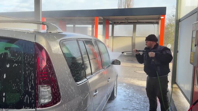 Man Washing Car at Self Service Car Wash Using High Pressure Water