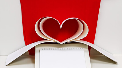 Open spiral bound notebook with heart shaped pages on red background