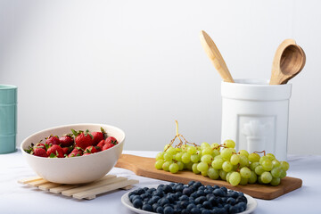 Containers with strawberries, blueberries, and green grapes.
