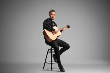 Male musician sitting on stool with an acoustic guitar