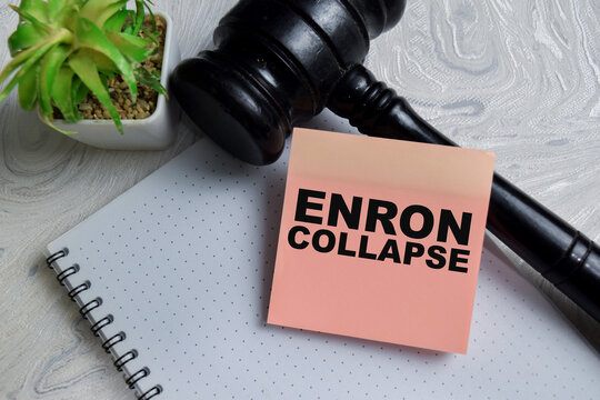 Concept of Enron collapse write on sticky notes isolated on Wooden Table. Representing corporate fraud, financial scandal and legal accountability
