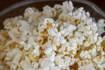 A close up view of the texture of freshly popped microwave popcorn in a clear bowl.