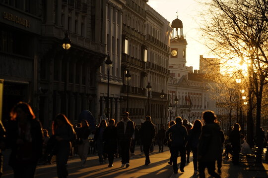 Luz de atardecer en la calle Acal&aacute; de la ciudad de Madrid con personas paseando y el foco puesto en el edificio del reloj Puerta del Sol. Madrid. Espa&ntilde;a