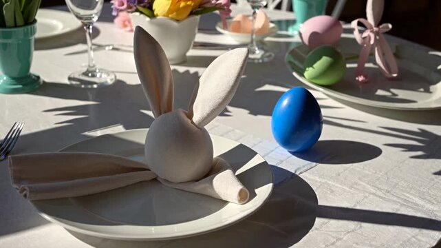 Elegant easter table with decorative bunny napkins and colorful eggs in sunlit dining setting