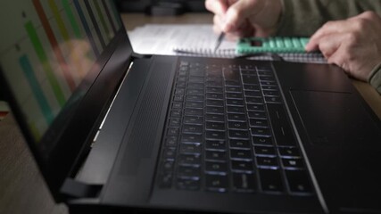 Close-up of a business workspace with a laptop displaying financial data, a calculator and handwritten notes. Concept of budgeting, financial planning, expense control, business strategy. - Powered by Adobe