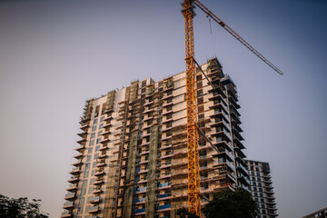 Construction site in Dubai featuring a high-rise building under development with a crane and scaffolding visible against a clear sky