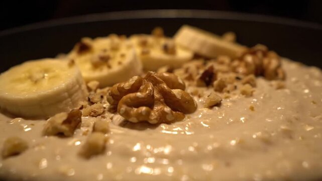 A continental breakfast creamy oatmeal topped with sliced bananas and whole walnuts.