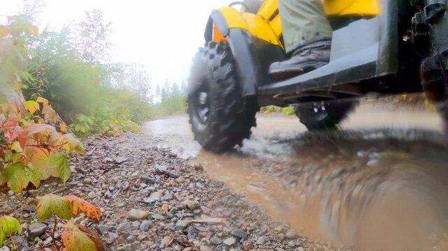 ATV rider steps down from yellow ATV off-road OHV rainy wet day mud