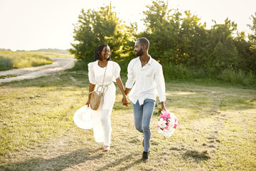 African newlyweds walking with bouquet in nature