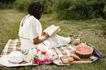 African girl relaxing with the book on a picnic