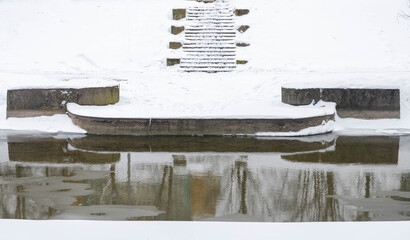 Granite stairs and terrace over the river under snow in winter