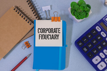 On a light gray background, a notebook, a blue pen and a sheet of paper with the text FIDUCIARY DUTY