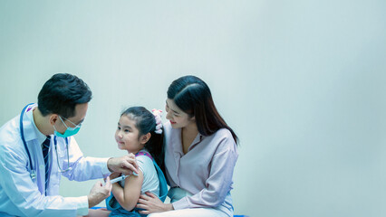 Fototapeta premium Doctor administering a vaccine to a young girl in a hospital, with her mother standing nearby to provide care and emotional support.