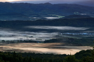 Obraz premium 黒松内町の山より望む朝日に染まる雲海に覆われた農村風景