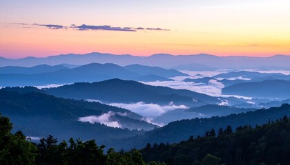 Obraz premium A scenic panoramic view of layers of mountains during dawn or dusk, with wisps of fog in the valleys and a colorful sky