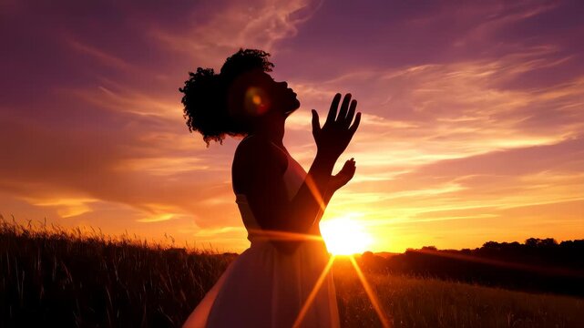 Woman praying looking up with hands open to sky silhouette beautiful sunset