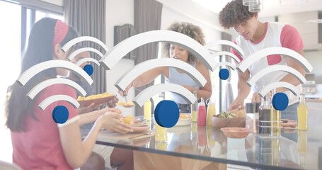 Sharing breakfast, four adults in casual wear reaching around glass kitchen island with WiFi icons