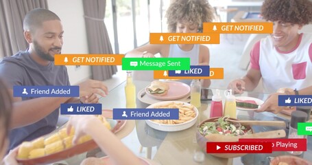 Sharing four friends in casual shirts passing plates at glass-top table, with food, phone, overlays