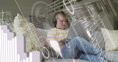 Sitting boy wearing yellow long-sleeve shirt, using tablet at home on sofa with headset, AR overlay