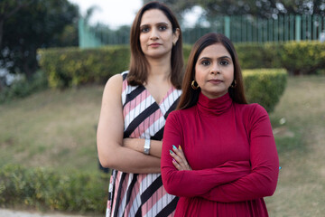 Obraz premium Two indian women arm crossed while looking at the camera at outdoor. Self independent women