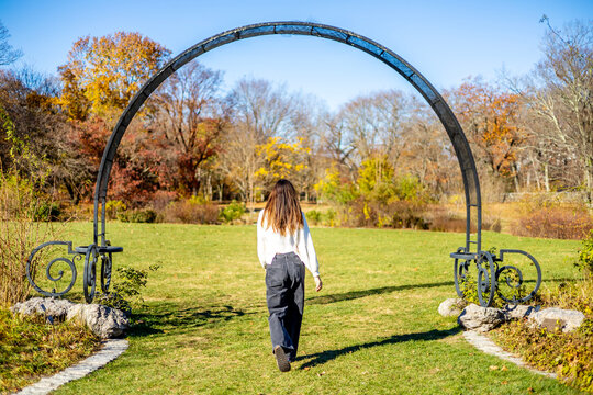 woman walking under an arch in a park