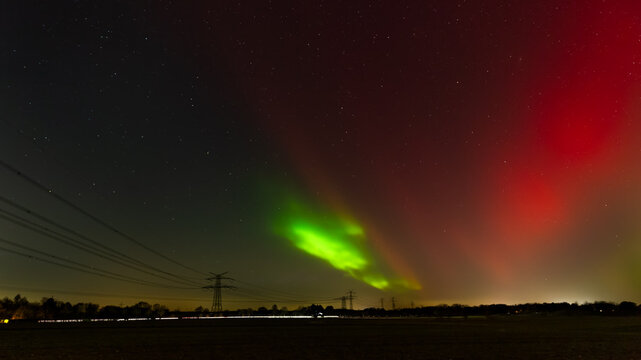 A spectacular view of the Aurora Borealis (Northern Lights) illuminating the night sky near Hamburg, Germany. 
The long-exposure photograph captures intense shades of green and rare red pillars stretc