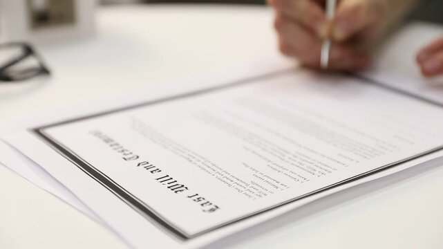 Woman signing Last Will and Testament at white table, closeup. Camera moving right