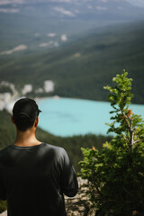 Man overlooking Lake Louise from a mountain viewpoint in Banff National Park. Scenic alpine landscape with turquoise water and forested valley