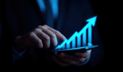 Hand holding a smartphone displaying a glowing blue digital bar chart with an upward arrow, representing financial growth and success