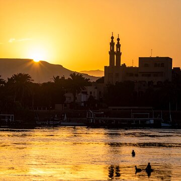 Sunset over Nile River, Mosque Minarets and Palm Trees Silhouette