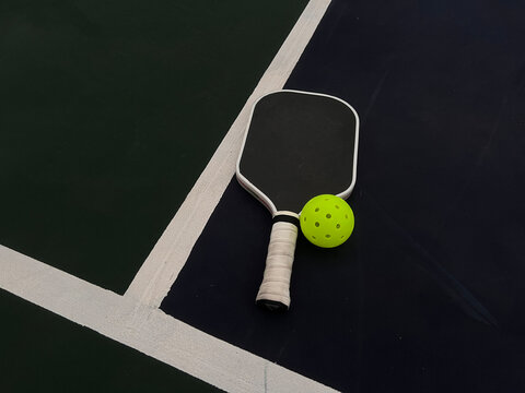 Pickleball paddle and ball in the blue and green court ground