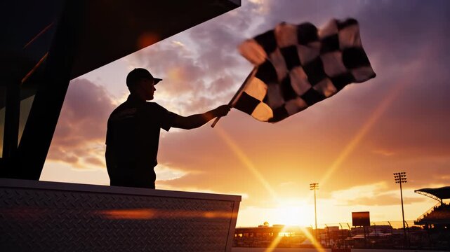 Race official waving checkered flag at sunset