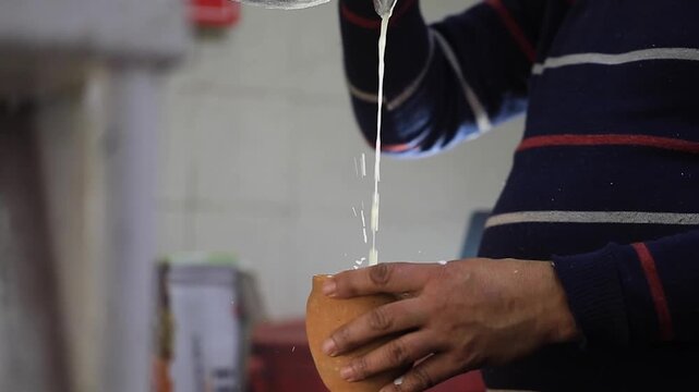 Closeup shot preparing sweet lassi. Juggling milk in utensil for making lassi.
