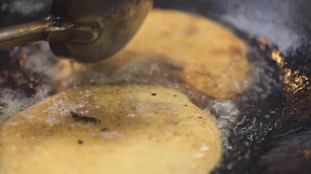 Closeup shot of deep frying Indian bread in oil.
Delhi famous street food.