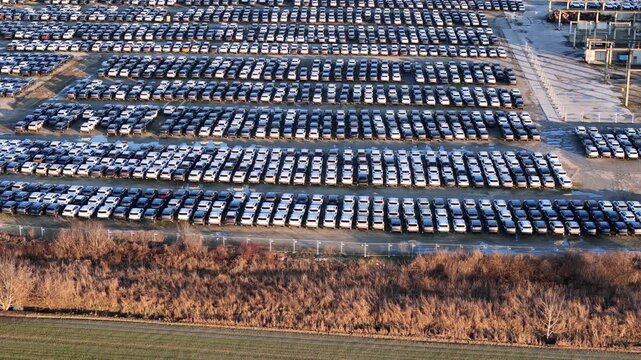 Drone panning documenting large scale automotive logistics, with imported vehicles stored in dense rows inside an industrial storage yard.